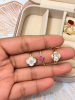 Three decorative gold rings with white and pink stones displayed on fingers